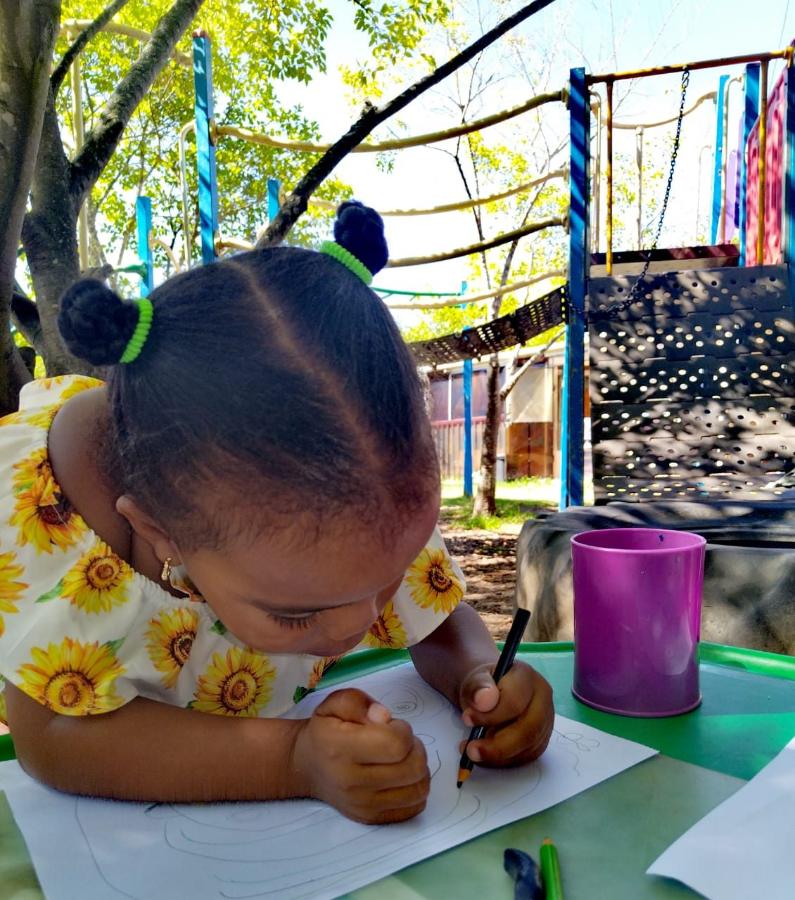 Girl drawing outside by the jungle gym