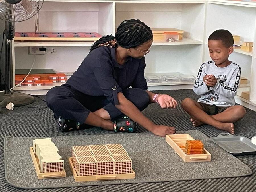 Teacher working with a boy and Montessori beads